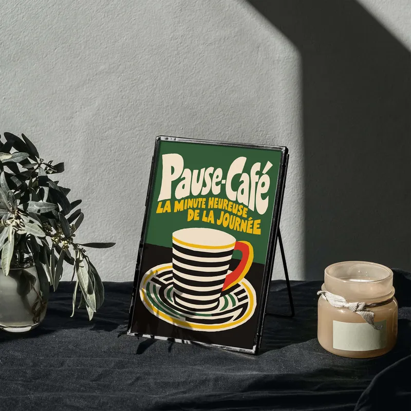 A small café-style corner with a Pause Café coffee print, a candle and a plant on a table